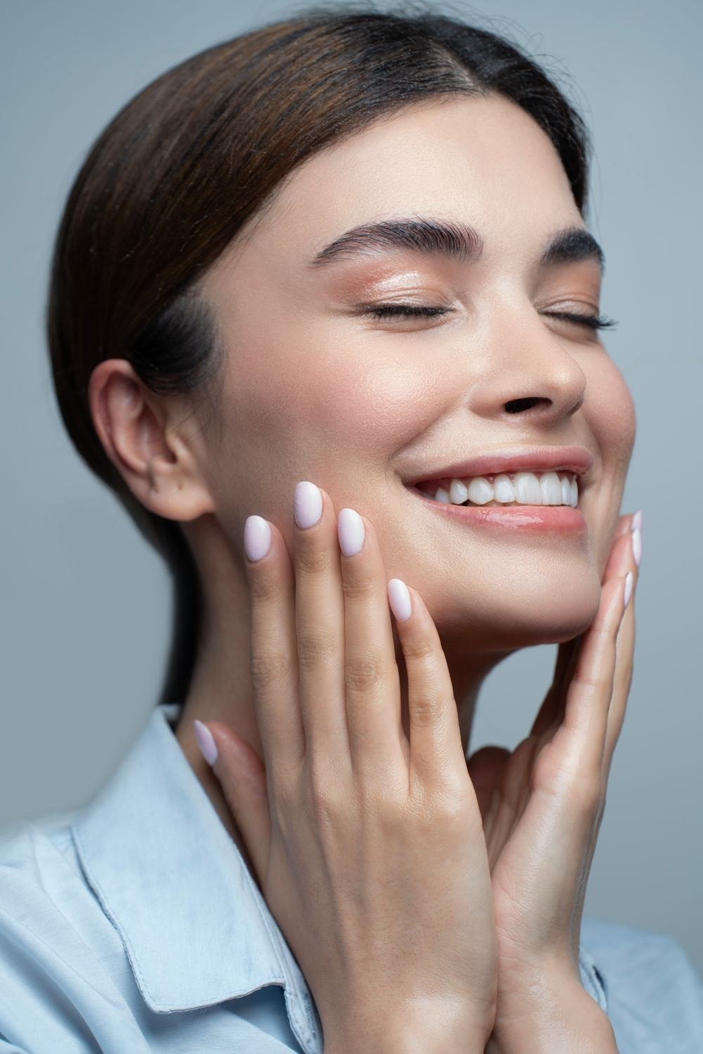 A woman smiling with relief, hands resting on her cheeks