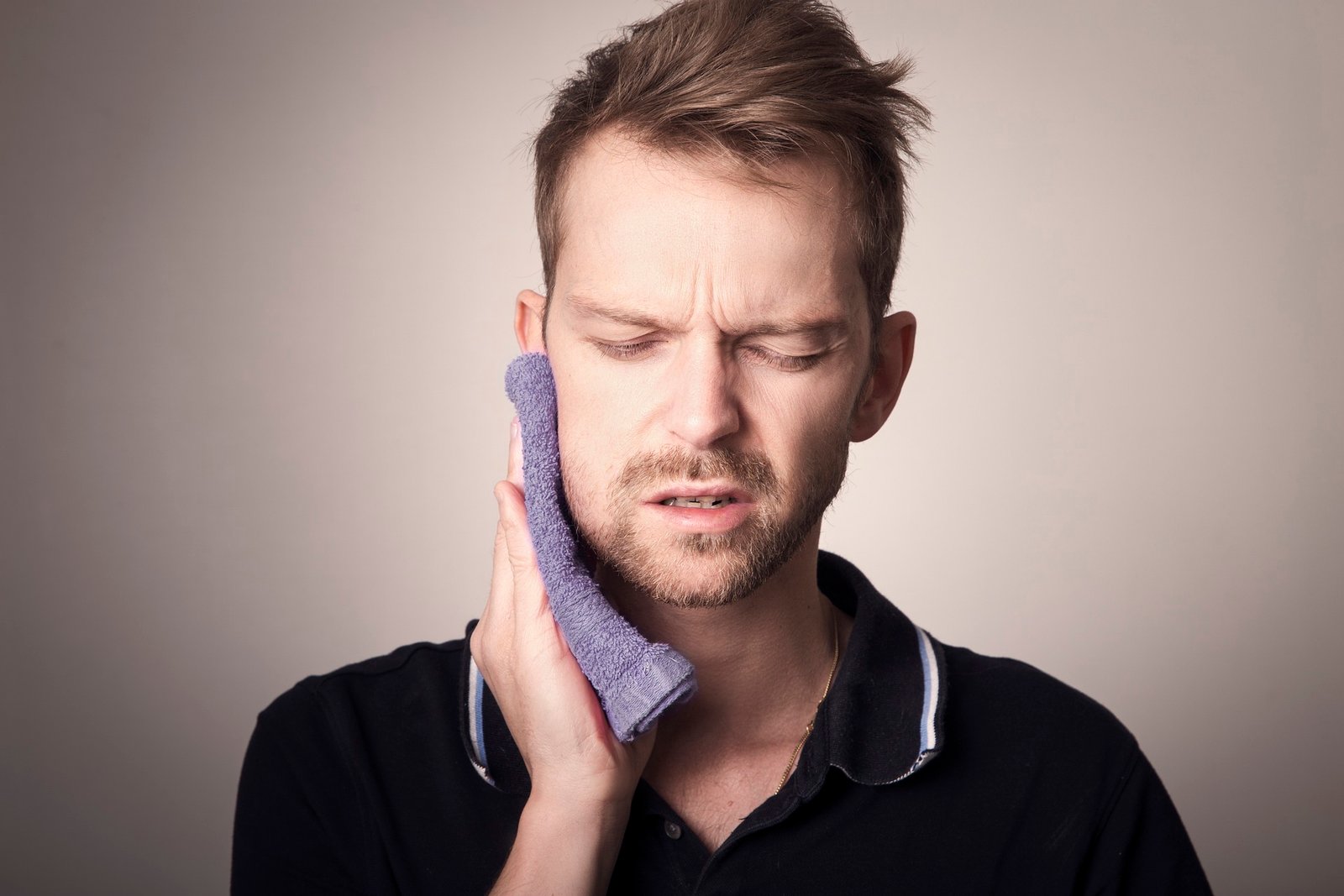 A man pressing a cold cloth against his cheek to ease a sore tooth